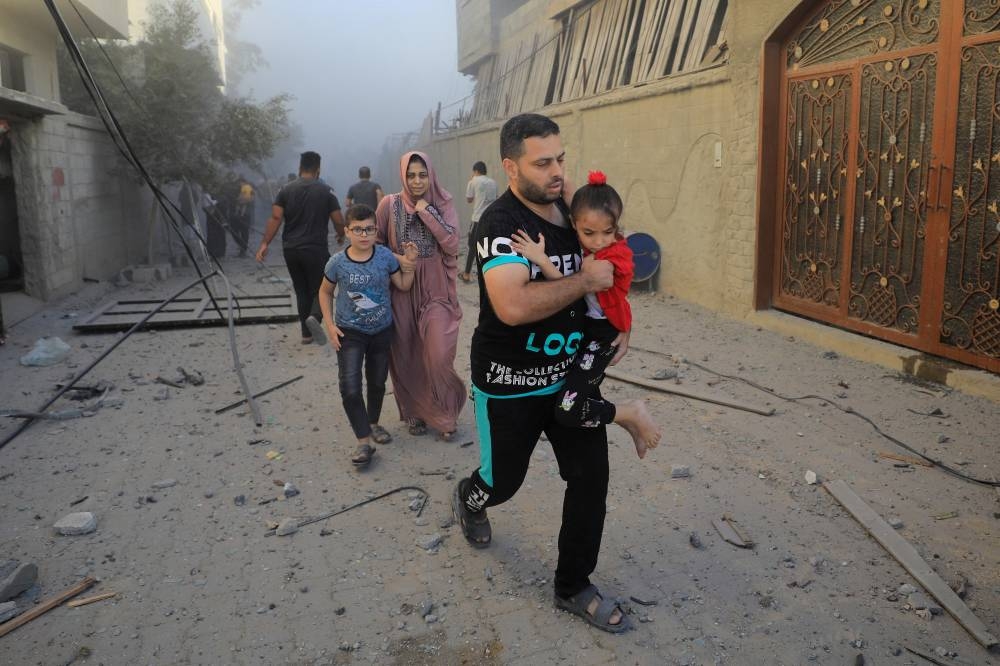 Palestinians evacuate the site of Israeli strikes on houses in Maghazi refugee camp in the central Gaza Strip, Monday. REUTERS