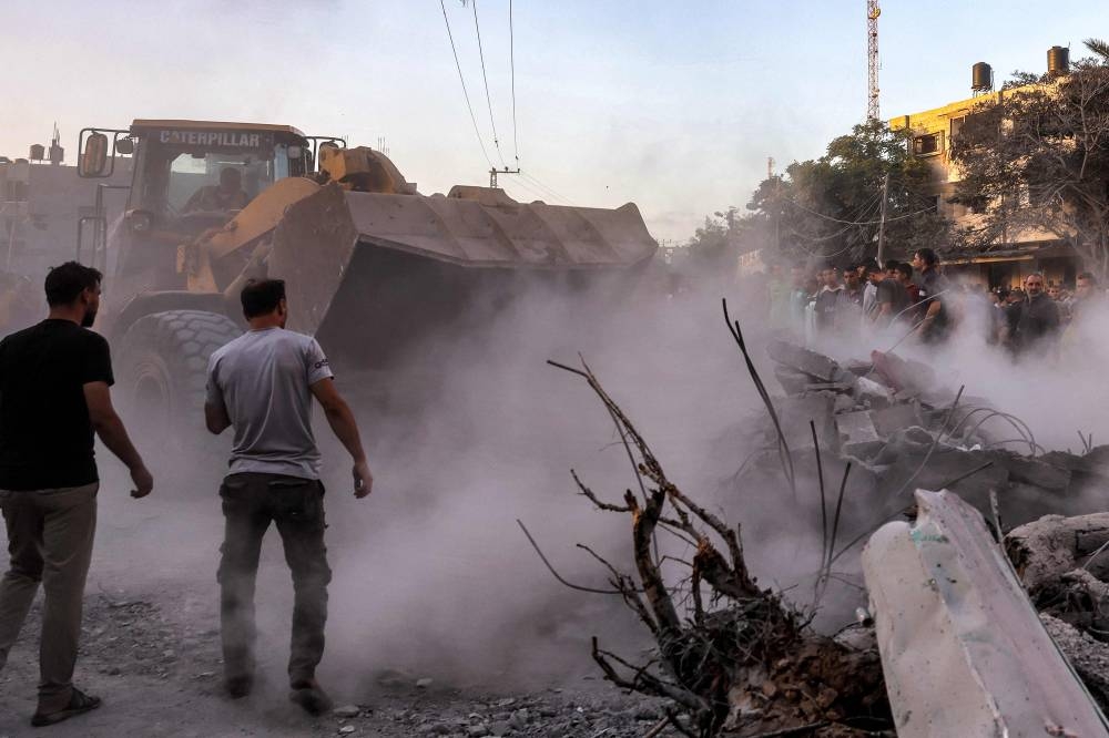 An excavator clears rubble as people search for survivors and the bodies of victims in the aftermath of Israeli bombardment in Rafah in the southern Gaza Strip on Monday. AFP