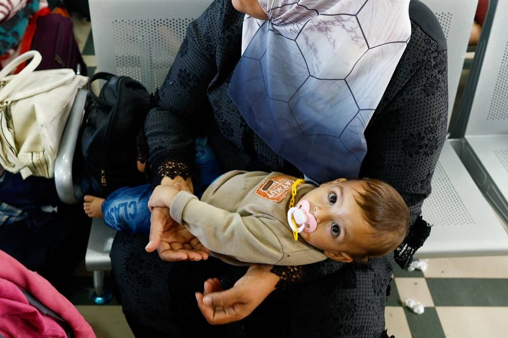 A baby looks on as Palestinians with foreign passports wait for permission to leave Gaza at the Rafah border crossing with Egypt, in Rafah in the southern Gaza Strip, on Tuesday. REUTERS