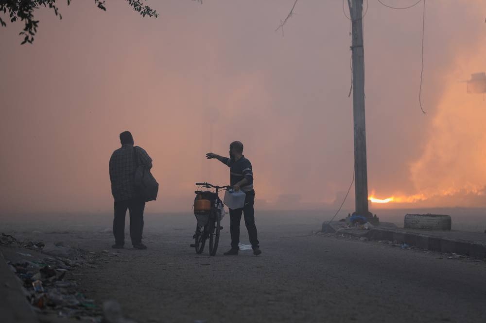 A man gestures as he walks with his bike during Israel's ground offensive, on the edges of Beach refugee camp, in Gaza City, Wednesday. REUTERS