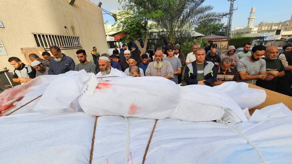 Mourners pray next to the bodies of Palestinians from the Daher family, who were killed by Israel strikes, at Indonesia Hospital in the northern Gaza Strip, Wednesday. REUTERS