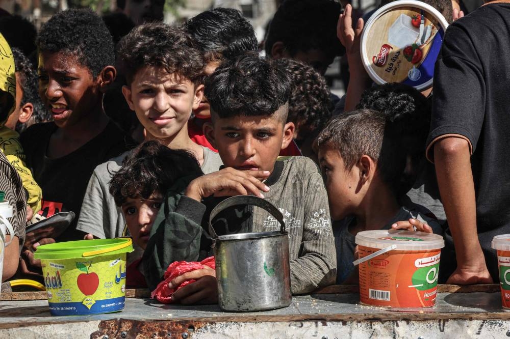 Palestinian children queue to receive a portion of food at a make-shift charity kitchen in Rafah in the southern Gaza Strip, on Wednesday. AFP