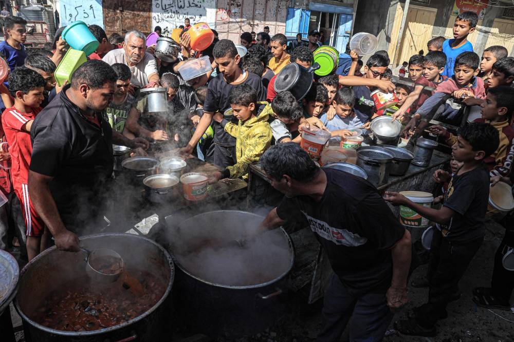 Palestinians queue to receive a portion of food at a make-shift charity kitchen in Rafah in the southern Gaza Strip, on Wednesday. AFP