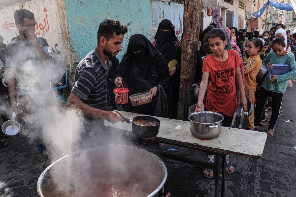 Palestinians queue to receive a portion of food at a make-shift charity kitchen in Rafah in the southern Gaza Strip, on Wednesday. AFP