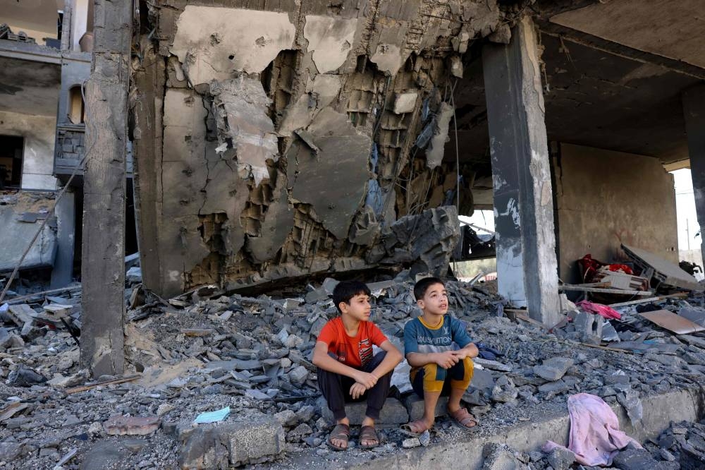 Children sit amid the rubble of a building in the aftermath of an Israeli strike in Rafah in the southern Gaza Strip, on Friday. AFP