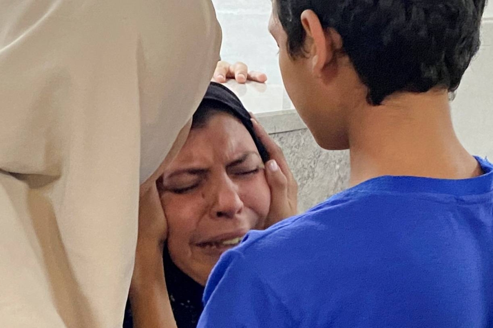 The mother of Palestinian Mohammed Abu Amira, who was killed in an Israeli strike, is comforted by her son as she breaks down at Al Shifa hospital in Gaza City, on Friday. REUTERS