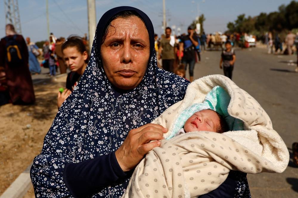 Palestinian woman Um Hussein holds her granddaughter, who she said was born today, while she moves southward after fleeing north Gaza as Israeli tanks roll deeper into the enclave, on Friday. REUTERS