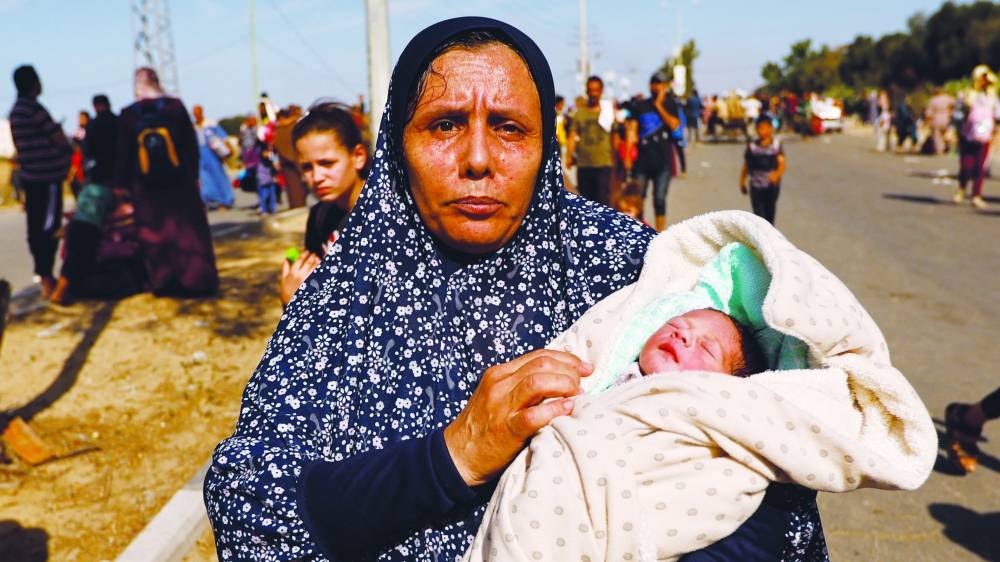 
Palestinian woman Um Hussein holds her granddaughter, who she said was born yesterday, while she moves southward after fleeing north Gaza, in the central Gaza Strip, yesterday. 