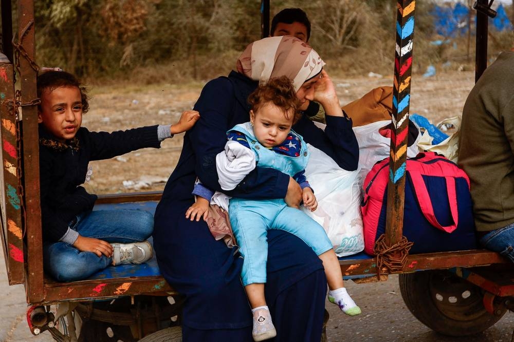 A woman holds a child while Palestinians flee north Gaza to move southward, as Israeli tanks roll deeper into the enclave in the central Gaza Strip, on Sunday. REUTERS