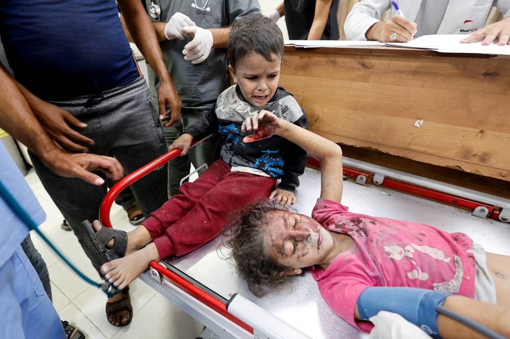 A boy reacts next to a wounded Palestinian child following an Israeli strike, at a hospital as they seek medical treatment, in Khan Younis in the southern Gaza Strip, on Sunday. REUTERS