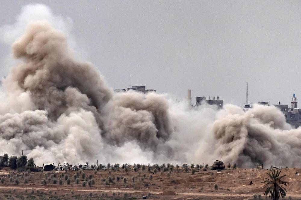 An Israeli tank and a plume of smoke erupting during Israeli bombardment on the Palestinian enclave amid ongoing battles, on Sunday. AFP