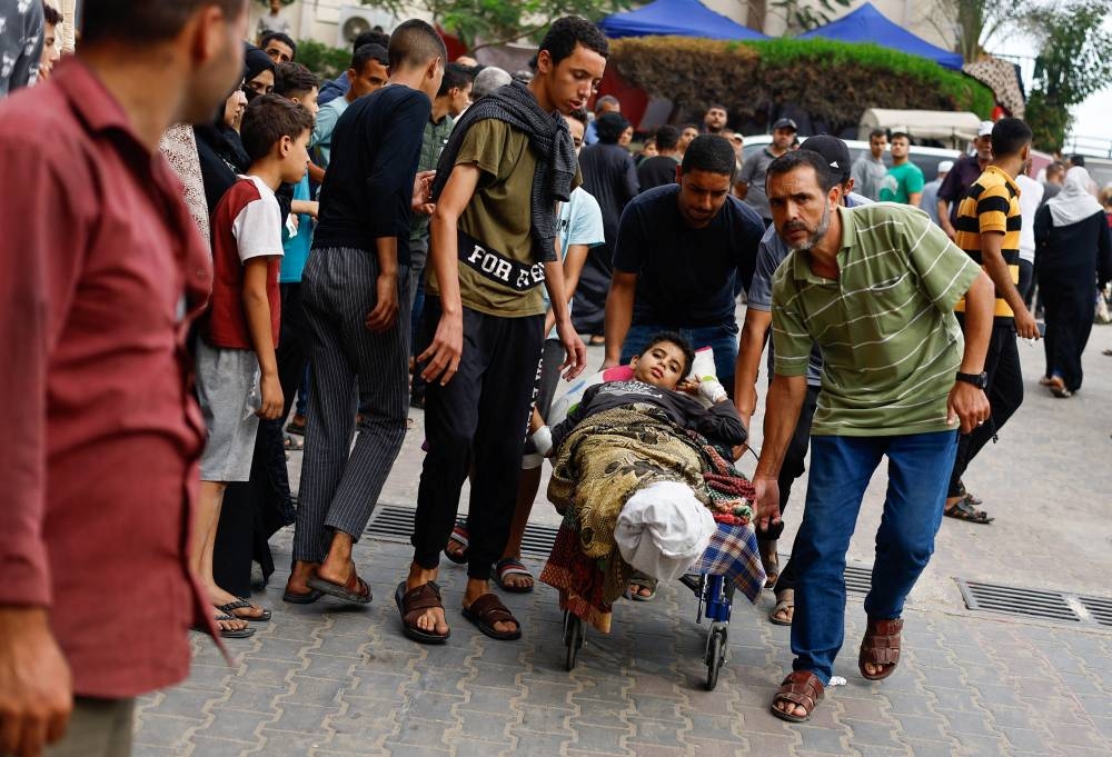 People aid a Palestinian wounded in Israeli strikes in Khan Younis in the southern Gaza Strip, on Sunday. REUTERS