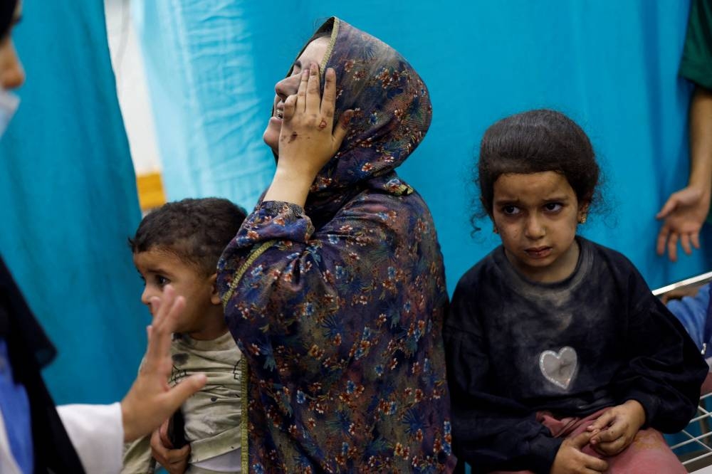 A woman reacts while sitting with Palestinian children wounded in Israeli strikes waiting to receive treatment at Nasser hospital in Khan Younis in the southern Gaza Strip on Sunday. REUTERS