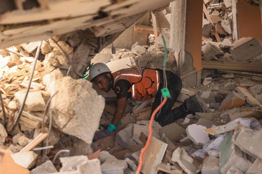 A rescuer looks for survivors amid the rubble of a destroyed building following an Israeli bombardment in Khan Yunis in the southern Gaza Strip on Sunday. AFP