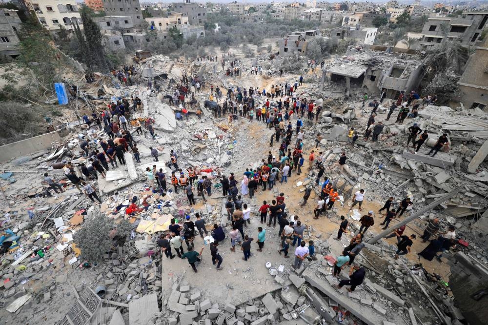 Rescuers and civilians stand amid the rubble of a destroyed building following an Israeli bombardment in Khan Yunis in the southern Gaza Strip on Sunday, AFP