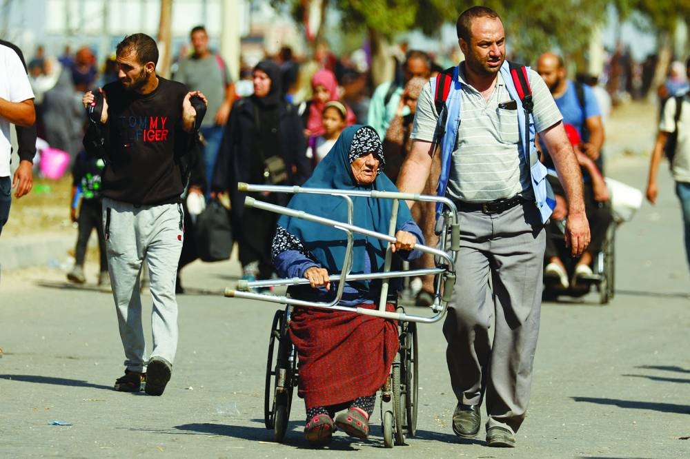 
A woman rides a wheelchair while Palestinians flee north Gaza to move southward, amid the ongoing conflict, in the central Gaza Strip. 