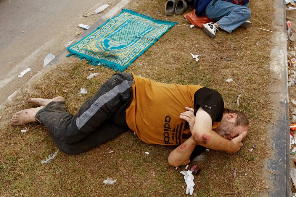 A Palestinian man, who was wounded in an Israeli strike and was staying at Al Shifa hospital, rests on the road as he flees from north Gaza to the south, as Israeli tanks roll deeper into the enclave in the central Gaza Strip, on Monday. REUTERS