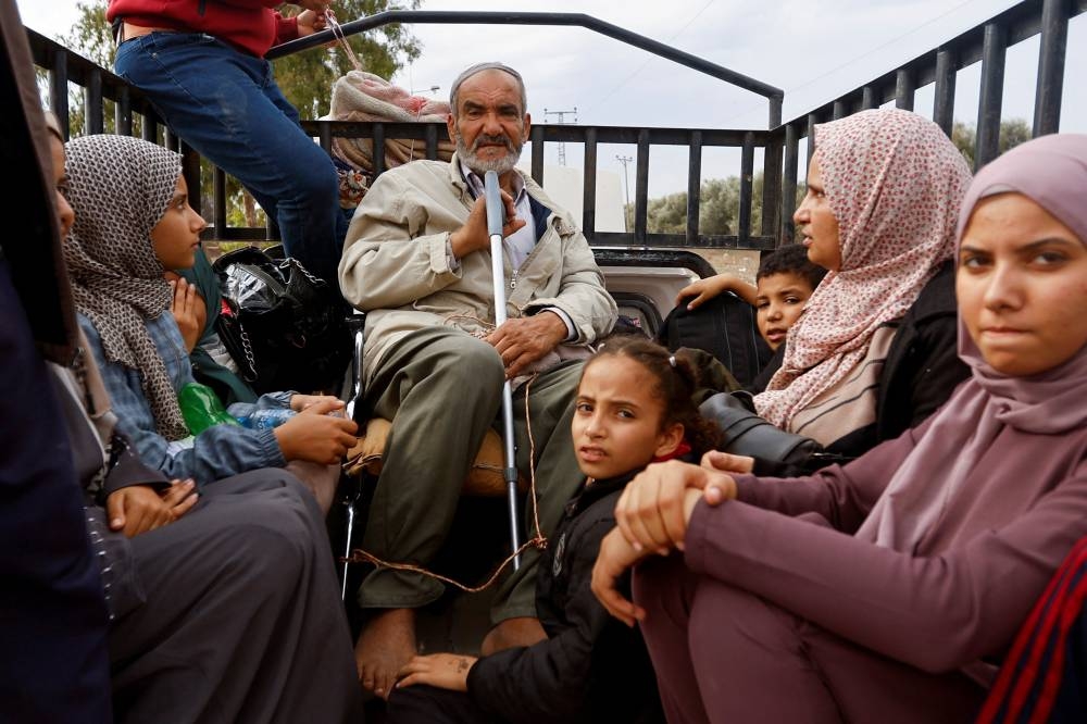 Palestinians fleeing north Gaza ride in the back of a truck as they move southward, as Israeli tanks roll deeper into the enclave in the central Gaza Strip, on Monday. REUTERS