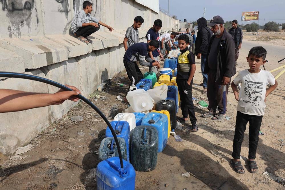 Palestinian children fill containers with water in Rafah, in the southern Gaza Strip on Monday. AFP