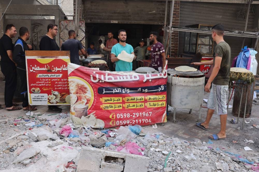Palestinians make bread amid debris of destroyed buildings in Rafah, in the southern Gaza Strip on Monday. AFP