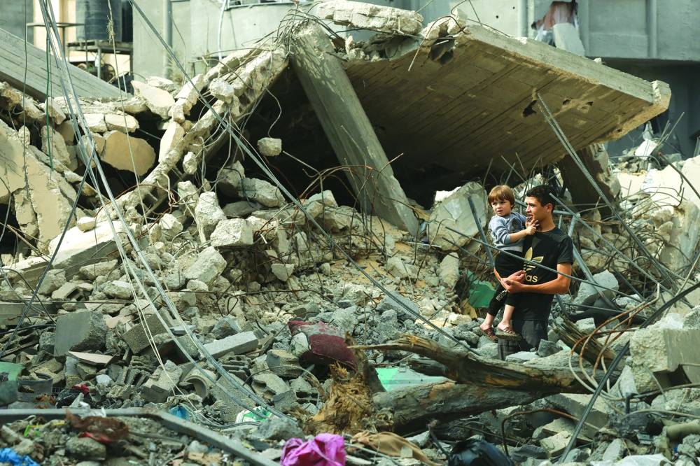 A Palestinian youth holds his younger brother as they stand amid debris of a destroyed building in Rafah, in the southern Gaza Strip,yesterday.