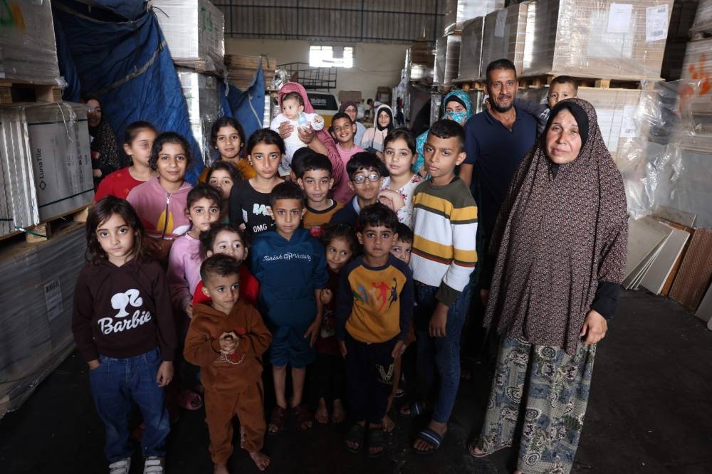 Children and their families pose for a photograph inside a large ceramic's shop where they are currently living in Bureij, in the central of Gaza Strip, on Tuesday. AFP