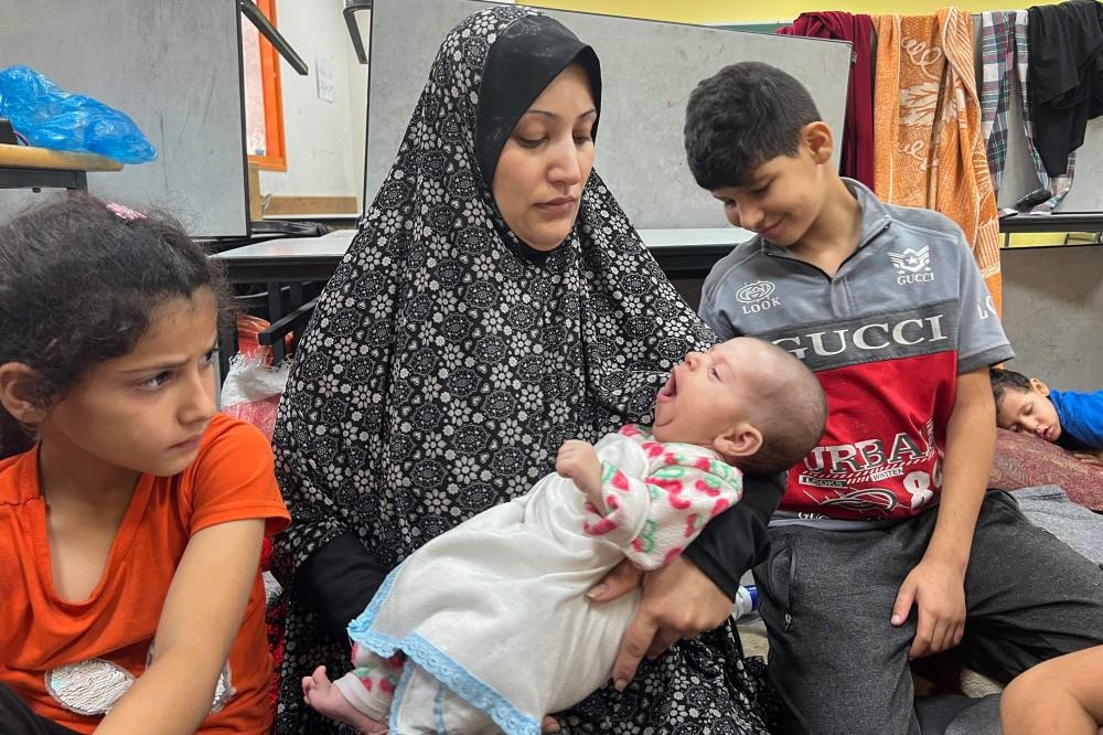 Fadwa Kullab carries her newborn Mohammad at a United Nations Relief and Works Agency for Palestine Refugees in the Near East (UNRWA) in Rafah in the southern Gaza Strip, on Tuesday. AFP