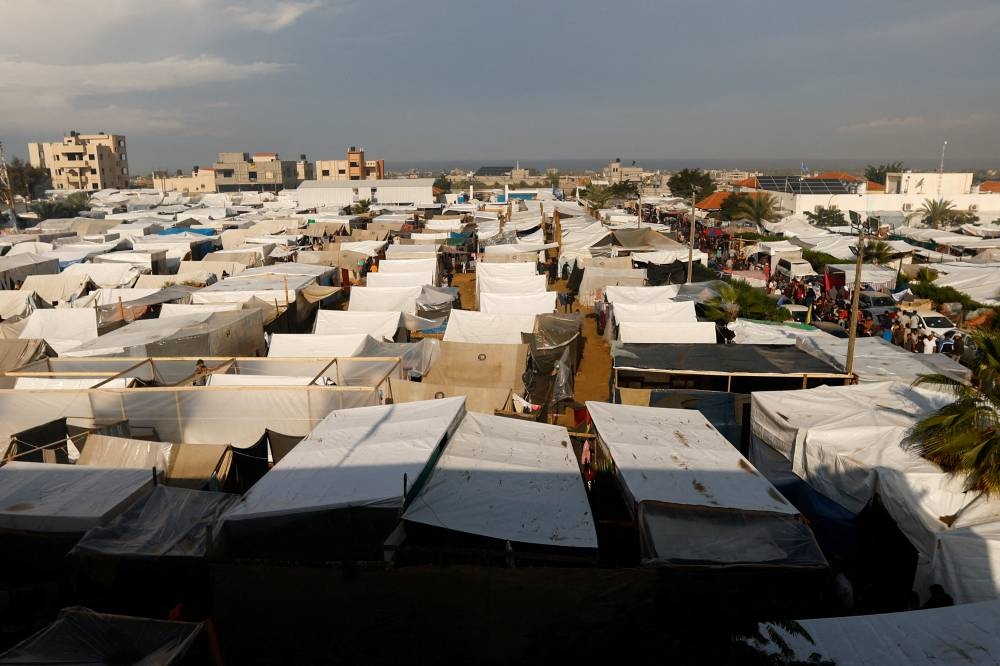 People walk at a tent camp sheltering displaced Palestinians in Khan Younis in the southern Gaza Strip, on Tuesday. REUTERS
