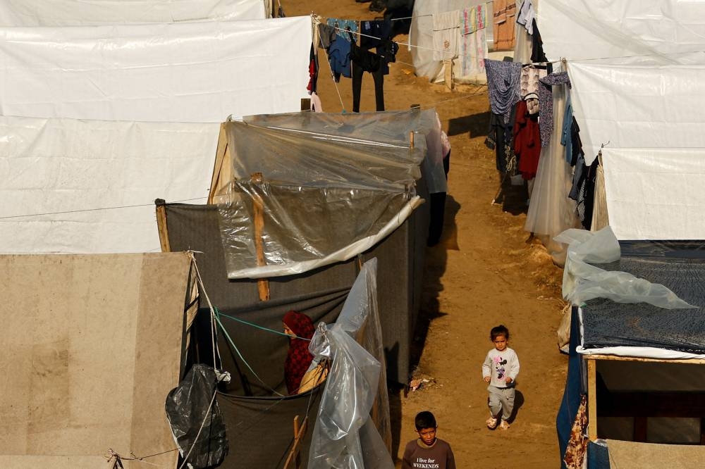 Children walk at a tent camp sheltering displaced Palestinians following a rainfall, in Khan Younis in the southern Gaza Strip, on Tuesday. REUTERS