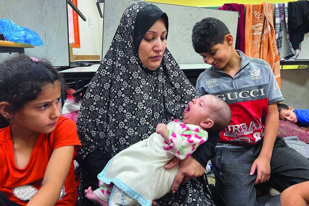 
Fadwa Kullab carries her newborn son, Mohamed at a UN Relief and Works Agency for Palestine Refugees in the Near East (UNRWA) shelter in Rafah in the southern Gaza Strip. 