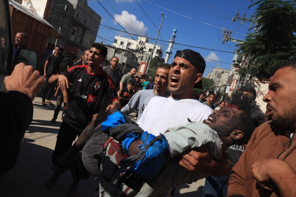 A man evacuates a wounded man after Israeli bombardment in Rafah in the southern Gaza Strip, on Friday. AFP