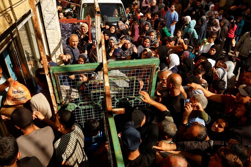 Palestinians queue as they wait to buy bread from a bakery, amid shortages of food supplies and fuel, in Khan Younis in the southern Gaza Strip, on Friday. REUTERS