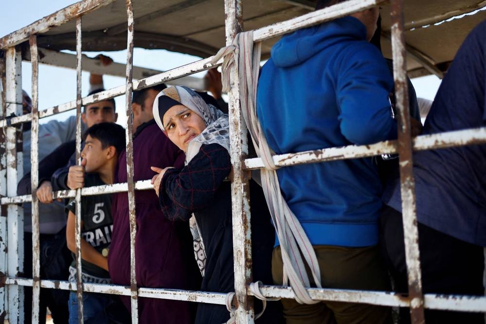 Palestinians sit at the back of a truck as they flee north Gaza and move southward, as Israeli tanks roll deeper into the enclave, in the central Gaza Strip, on Saturday. REUTERS