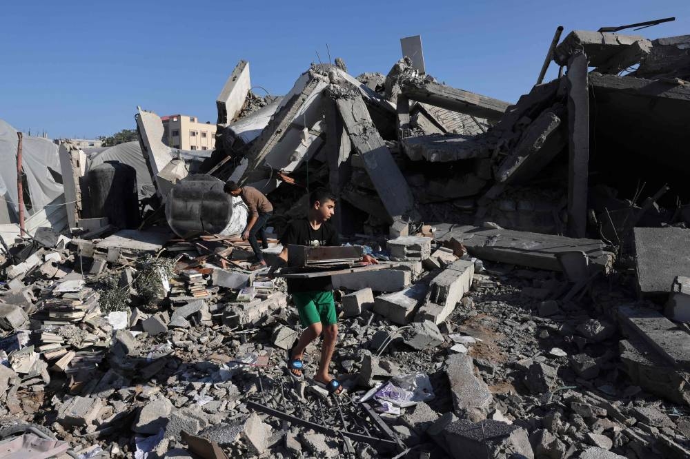 Palestinians collect books from the rubble of a cultural centre following an Israeli strike in Rafah in the southern Gaza Strip, on Saturday. AFP