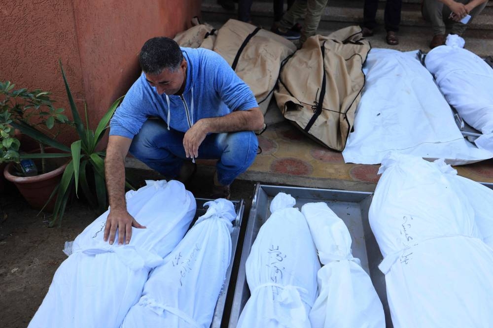 A Palestinian man mourns over the bodies of relatives, killed in Israeli bombardment, in Khan Yunis in the southern Gaza strip, on Saturday. AFP