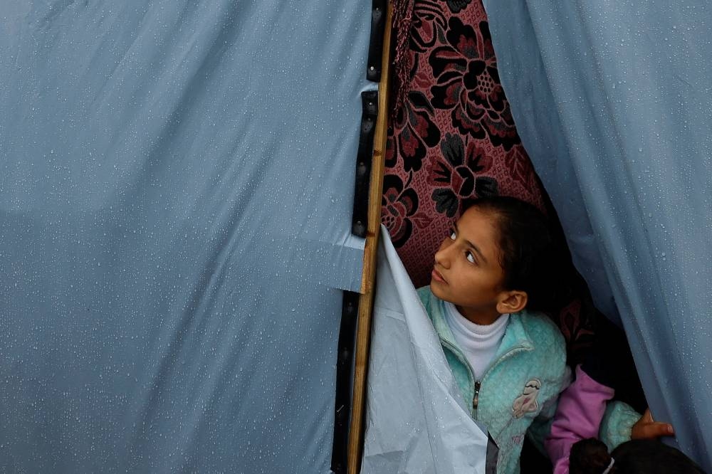 A Palestinian child looks out from a tent following a rainfall in Khan Younis in the southern Gaza Strip,, on Sunday. REUTERS