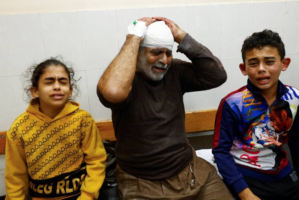 A Palestinian man wounded in an Israeli strike reacts next to children at Nasser hospital in Khan Younis in the southern Gaza Strip, on Monday. REUTERS