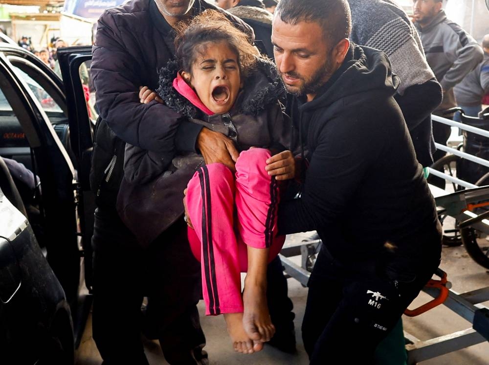 A Palestinian child wounded in an Israeli strike is carried at Nasser hospital in Khan Younis in the southern Gaza Strip, on Monday. REUTERS