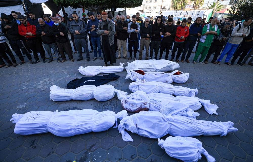 Palestinians pray during the funeral of Al Hajj family at the Al-Aqsa Hospital in Deir el-Balah, in the central Gaza Strip, on Tuesday. AFP