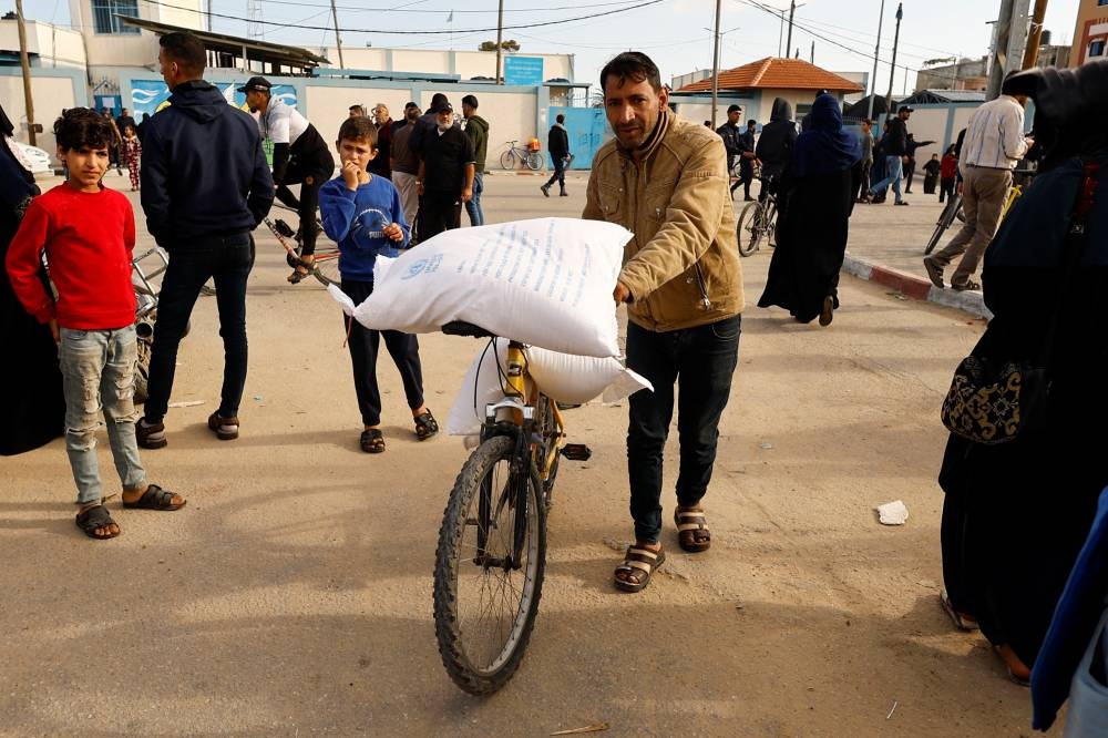 A Palestinian carries flour bags distributed by UNRWA in Rafah, in the southern Gaza Strip, on Tuesday. REUTERS