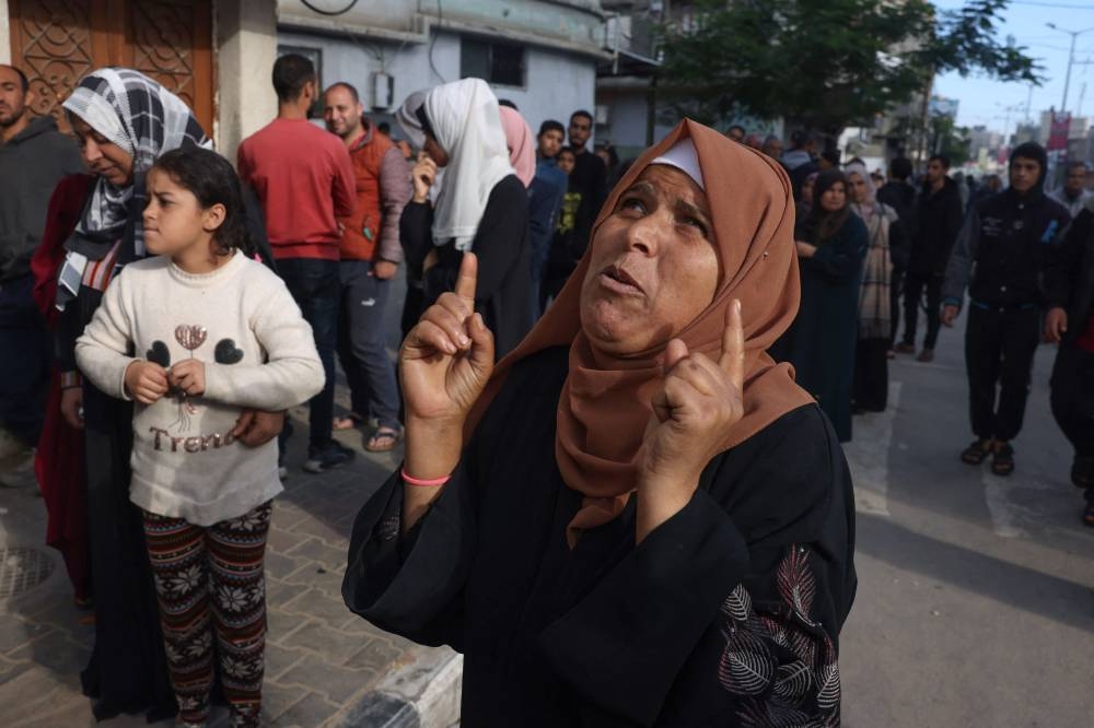 A woman gestures as Palestinians wait to buy bread in Khan Yunis in the southern Gaza Strip, on Tuesday. AFP