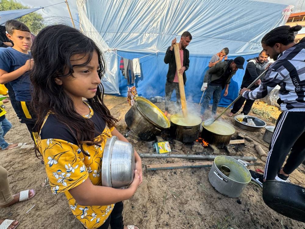 Children wait while displaced Palestinians, who fled their houses due to Israeli strikes, cook lentil soup on a rainy day at Nasser Hospital in Khan Younis in the southern Gaza Strip, on Tuesday. REUTERS