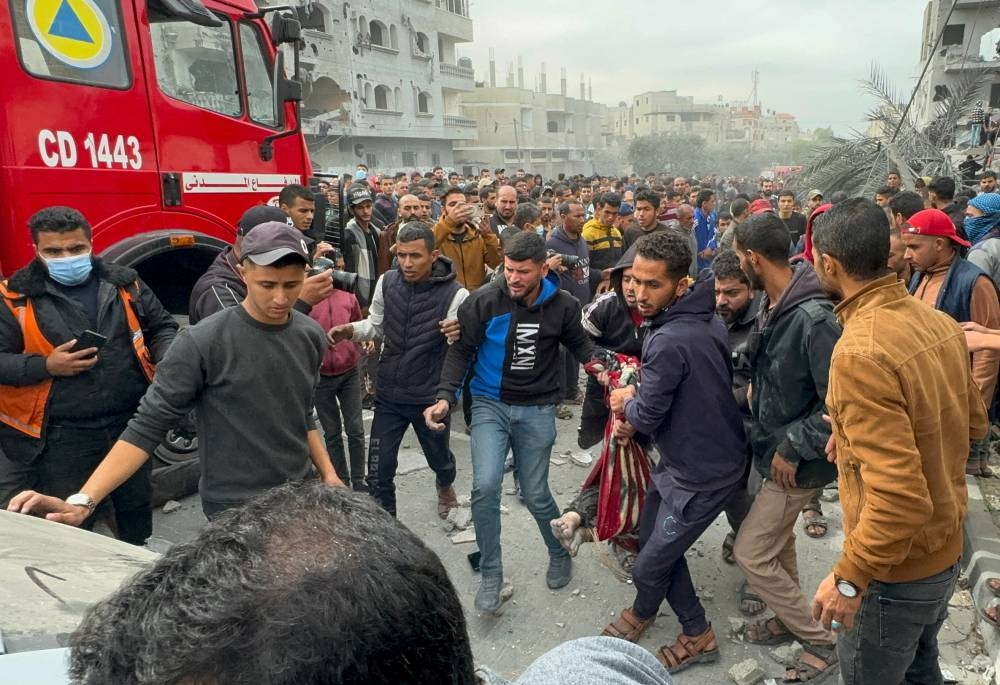 Palestinians carry a casualty, as others gather at the site of Israeli strikes on a house in Rafah in the southern Gaza Strip on Wednesday. REUTERS