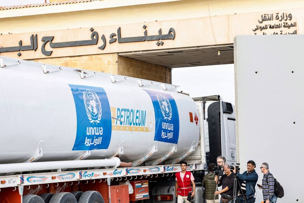 Media representatives work as a truck carrying humanitarian aid from the United Nations Relief and Works Agency for Palestine Refugees (UNRWA) arrives at the Egyptian side of the Rafah border crossing with the Gaza Strip on Wednesday. AFP