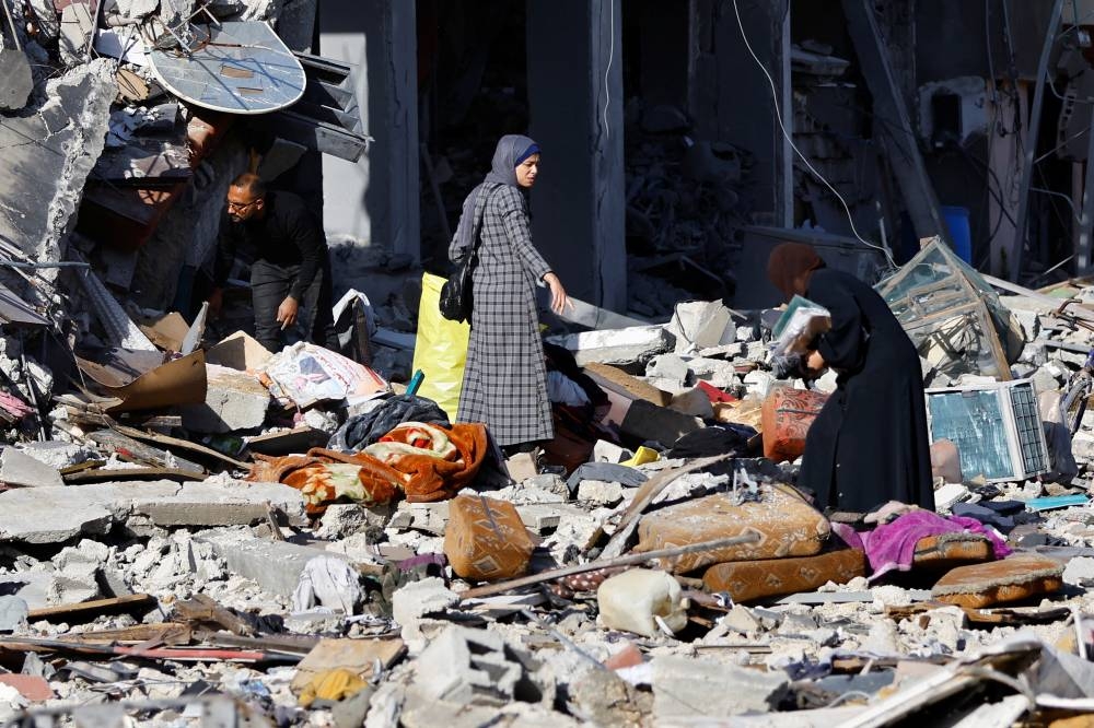 Palestinians stand among the rubble of a house destroyed in an Israeli strike during the conflict, amid the temporary truce between Hamas and Israel, in Khan Younis in the southern Gaza Strip on Friday. REUTERS