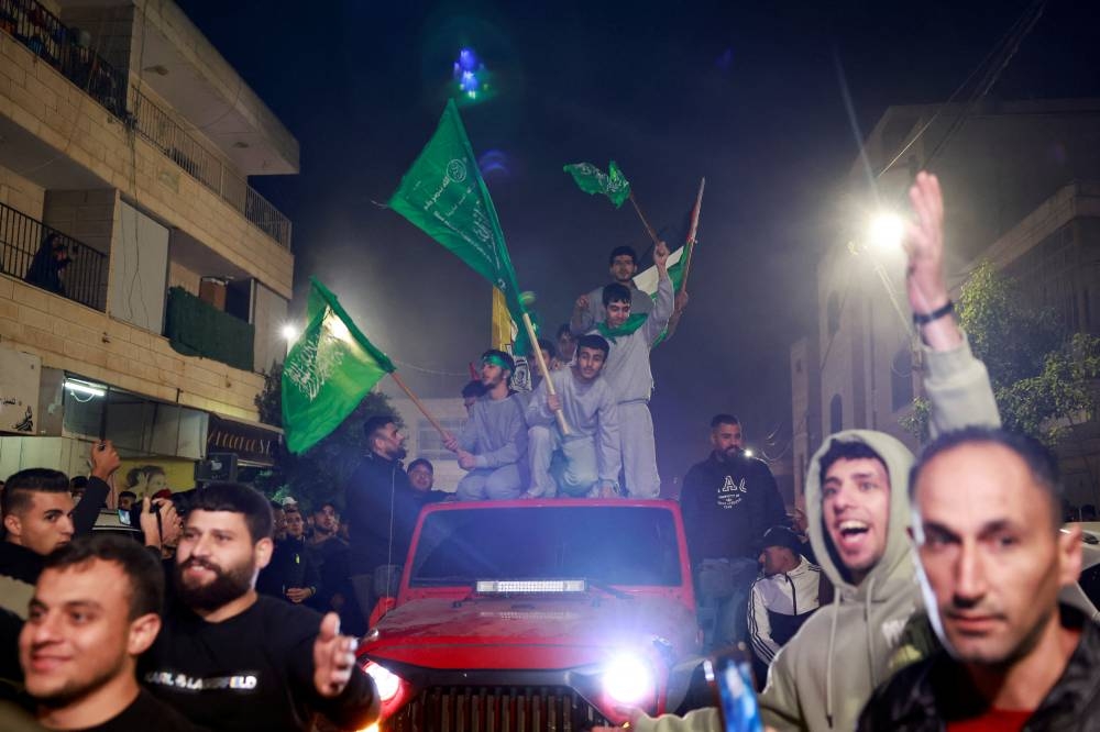 Released Palestinian prisoners wave flags atop a car as they leave the Israeli military prison, Ofer, on Friday. REUTERS