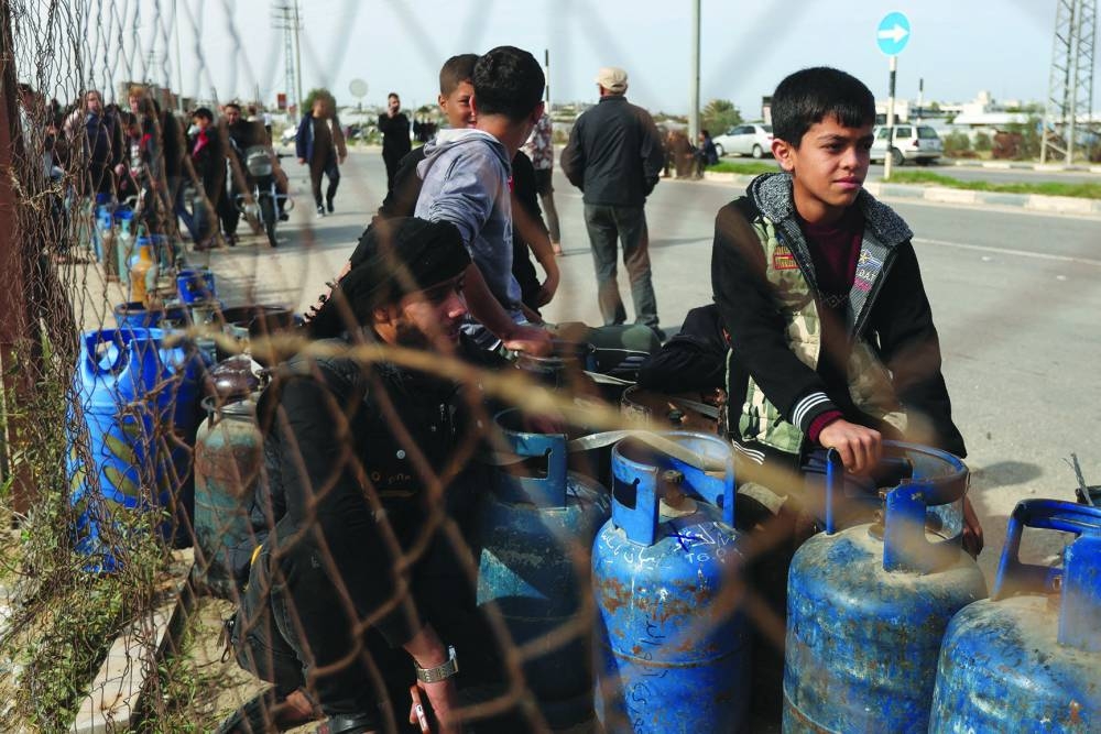 
Palestinians gather to fill liquid gas cylinders, during a temporary truce, in Rafah in the southern Gaza Strip, yesterday. 