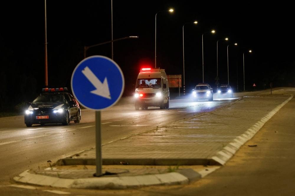 An ambulance believed to be carrying hostages released as part of a deal between Israel and Hamas, drives near the Israel-Gaza border, in Israel Sunday. REUTERS