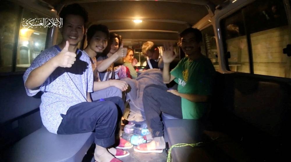 Hostages give a thumbs up as they are handed over by Hamas to members of the International Committee of the Red Cross in an unknown location in the Gaza Strip on Sunday. Hamas Military Wing/Handout via REUTERS