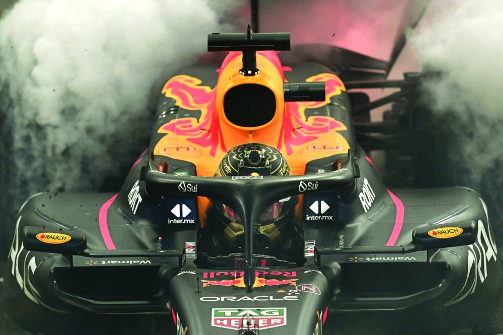 
Red Bull Racing’s Dutch driver Max Verstappen performs a burnout after winning the Abu Dhabi Grand Prix at the Yas Marina Circuit yesterday. Right: Max Verstappen celebrates with the trophy on the podium. (AFP) 